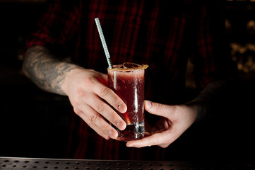 Bartender holding a Sippy Cup cocktail with a dried orange