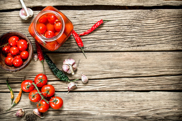 Pickled tomatoes in a glass jar with garlic and herbs.