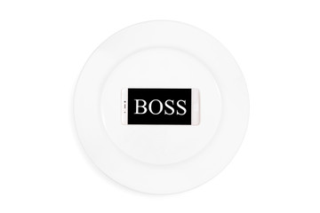 Word boss in the mobile phone on the plate on the white background. Top view. Concept. Isolated