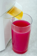 Juicer with a glass of red fresh juice in a modern kitchen.