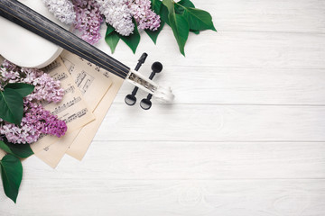 A bouquet of lilacs with violin and music sheet on a white wooden table. Top wiev with space for...