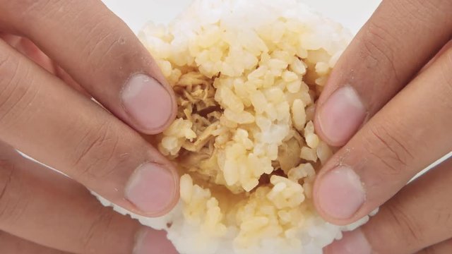 closeup of mans hand fracture an onigiri rice ball showing stuffing