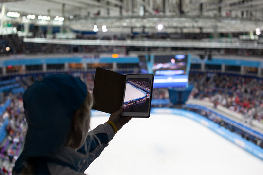 Girl writes video or takes pictures of figure skating competitions on the tablet