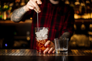 Bartender stirring a Foreign Legion cocktail with the spoon