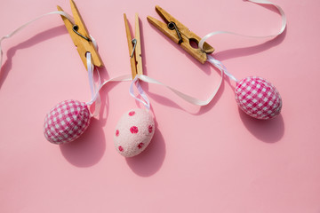 Easter scene with row of hanging colored eggs and pin isolated on pink background. Happy easter composition for spring greeting card.Copy space. Minimalism style. April event holiday concept