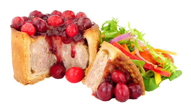 Pork pie topped with cranberries with fresh salad isolated on a white background