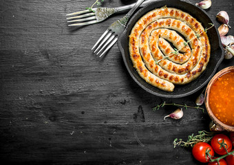 Fried sausage in a pan with garlic, tomatoes and herbs.