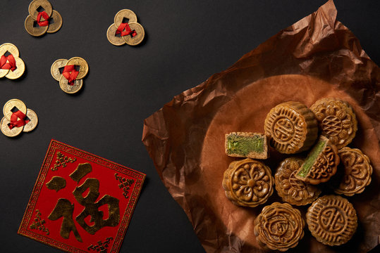 top view of traditional mooncakes with chinese talismans isolated on black