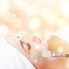 Attractive young woman applying mask on face with brush