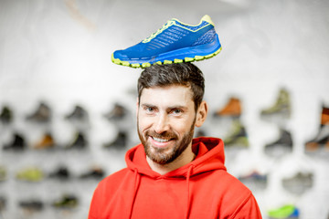 Funny portrait of a man with sports shoe on his head standing in the sports shop