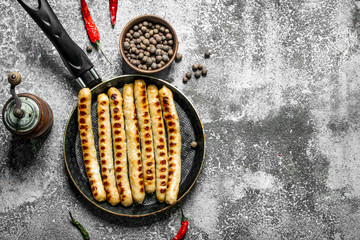Fried sausages with spices in a frying pan.