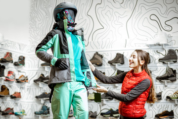 Happy woman choosing ski wear looking on the dummy at the luxury sports shop