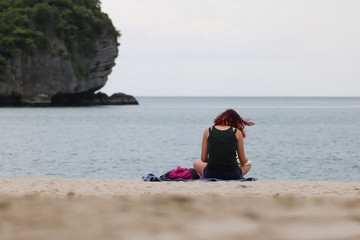Fototapeta premium Tourist girl reading a book relaxing on a tropical beach in the evening.