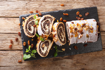 poppy beigli cake with raisins, walnuts decorated with icing and mint close-up on a table....