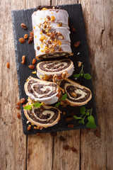 poppy beigli cake with raisins, walnuts decorated with icing and mint close-up on a table. Vertical...
