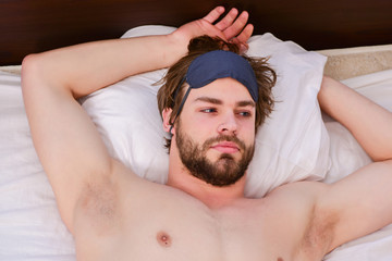 Feet of man sleeping in comfortable bed. Picture showing young man stretching in bed. Alarm clock with a man sleeping on bed.
