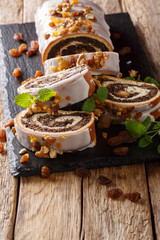 Traditional Polish poppy roll with raisins, walnuts and mint close-up on a table. vertical