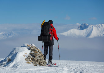 Hiker on snowshoes enjoying the moutain view at a cairn.