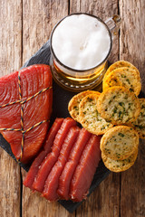 Foamy beer served with smoked tuna and toast with garlic and greens closeup. Vertical top view