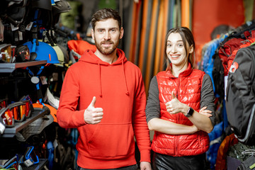 Portrait of a smiling man and woman as a sellers or clients in the shop with sports equipment