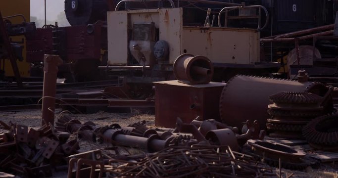 Scrap yard with rusty old trains parts and gears laying on ground