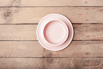 Fototapeta na wymiar Empty pink pastel colored plate and salad or soup bowl on grunge wood plank desk with copy space