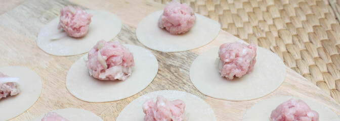 Raw dumplings, minced meat and dough on table