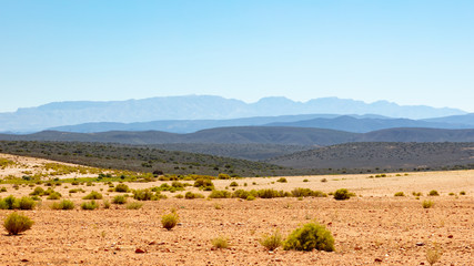 Fototapeta premium Dry tilled land with repeating mountains in different shades of blue