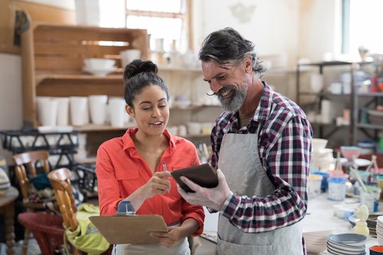 Male and female potter discussing over tablet pc 