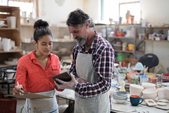 Male and female potter discussing over tablet pc  - Powered by Adobe