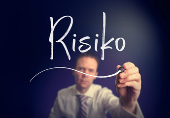 A businessman writing a Risk "Risiko" concept in German with a white pen on a clear screen.
