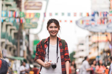 Traveler backpacker asian woman travel in Khao San road at Bangkok, Thailand. Happy young female spending holiday trip at amazing landmark and enjoy her journey in traditional city.