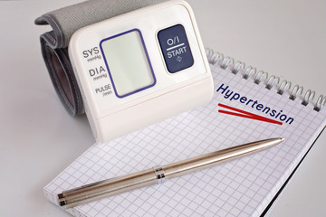 Diagnosis Hypertensive disease. Portable digital blood pressure monitor lie on sheet of paper with...
