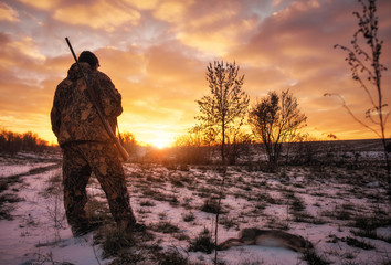 Winterjacht op hazen bij zonsopgang. Jager beweegt met jachtgeweer en zoekt naar prooi.