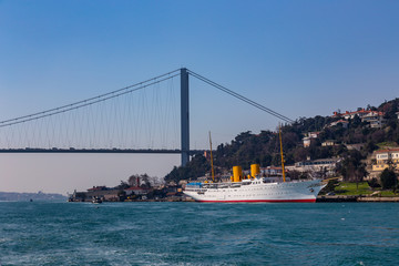 Fototapeta na wymiar The grand bridge of Sultan Mehmed Fatih through the Bosphorus and the sea ship, Turkey
