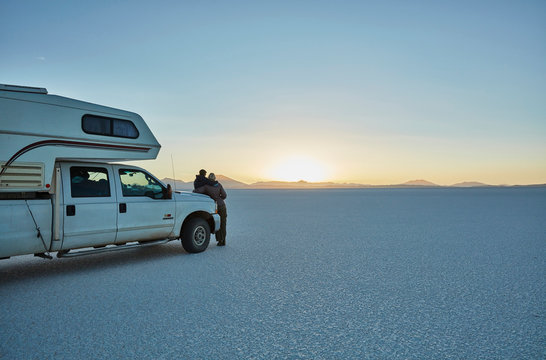 Bolivia, Salar de Uyuni, mother and son at camper on salt lake at sunset