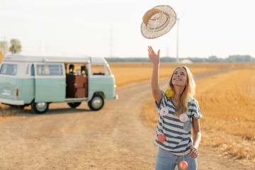 Happy young woman at camper van in rural landscape