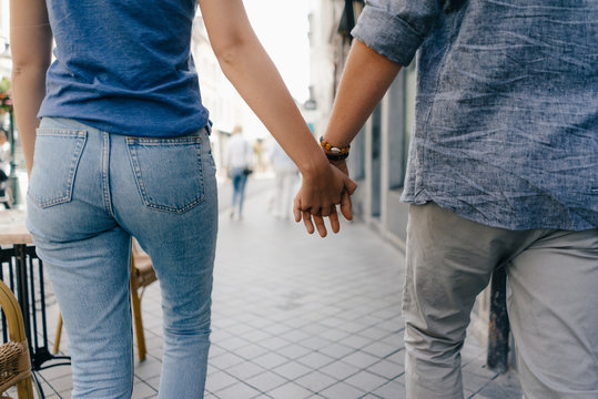 Netherlands, Maastricht, close-up of young couple walking hand in hand in the city