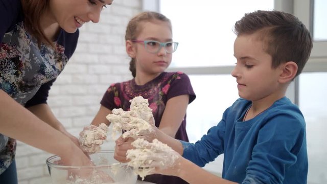 Mom touching son nose with flour. Close up of pretty kids have fun on kitchen