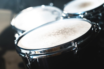 Closeup view of a drum set in a dark studio. Black drum barrels with chrome trim. The concept of live performances