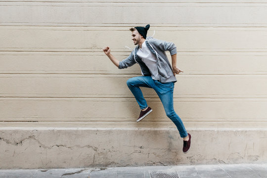 Happy young man jumping in front of a wall