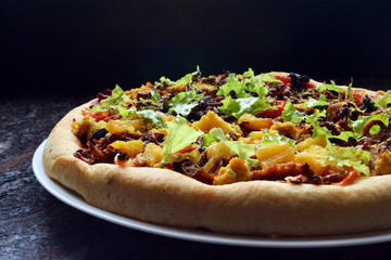 Thick, vegan pizza with tofu cheese, vegan soy sausages, mushrooms, capsicum, black olives, pineapple, tomatoes, lettuce and onions.