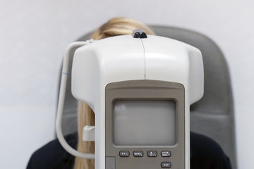 Women checks his vision on the machine checking patient vision at eye clinic or optics store. Face close-up. Focus on machine.