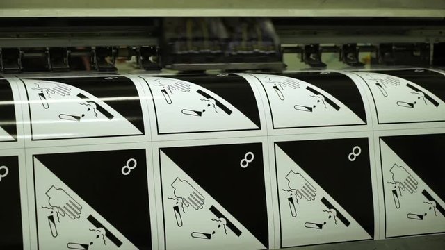 closeup large-format printer makes warning stickers for chemical lab with runner in typography