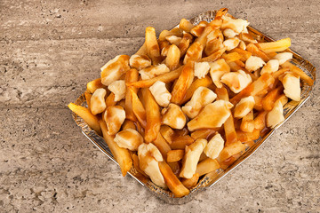 Close up on a poutine in a takeout container. Cooked with french fries, beef gravy and curd cheese. - 243675296