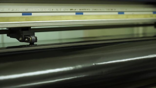 closeup powerful large format cutting machine operates with black polyethylene piece in typography