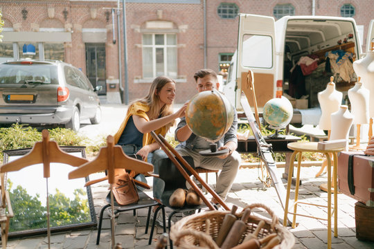 Belgium, Tongeren, young couple examining globe on an antique flea market