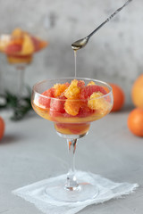 Salad of citrus and honey. Grapefruit, mandarin and orange in a glass on a dark background.
