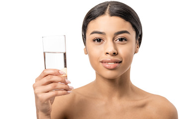 beautiful naked african american woman holding glass of water and smiling at camera isolated on white