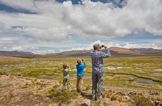 Peru, Chivay, Colca Canyon, father and sons taking pictures of swamp landscape in the Andes